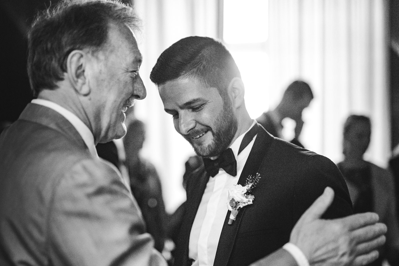 Vater gratuliert lächelnd dem Bräutigam, Schwarzweißaufnahme