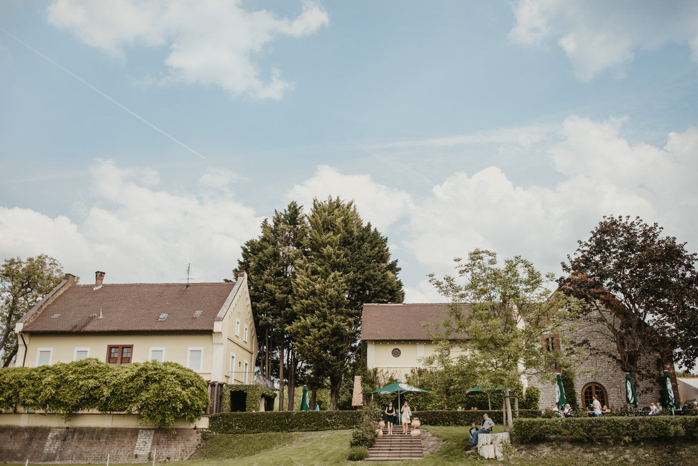 Gutshaus mit Bäumen unter weiten Wolken im Sommer