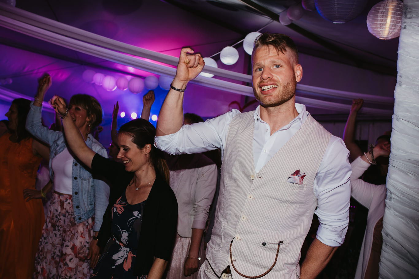 Gast tanzt ausgelassen mit erhobenen Armen unter Discolicht