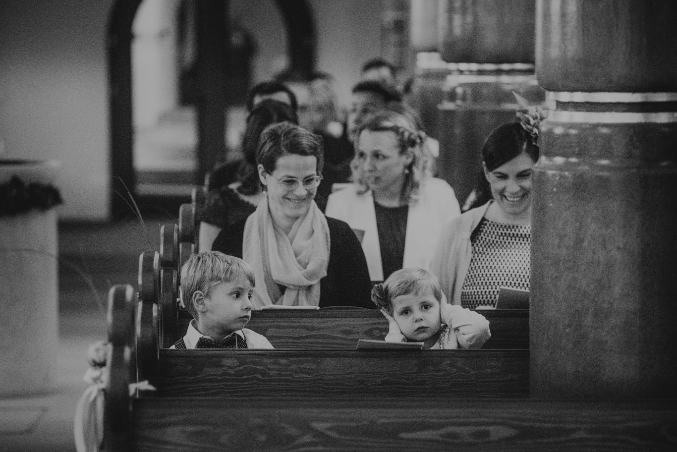 Kinder blicken neugierig über die Kirchenbank, Schwarzweißaufnahme