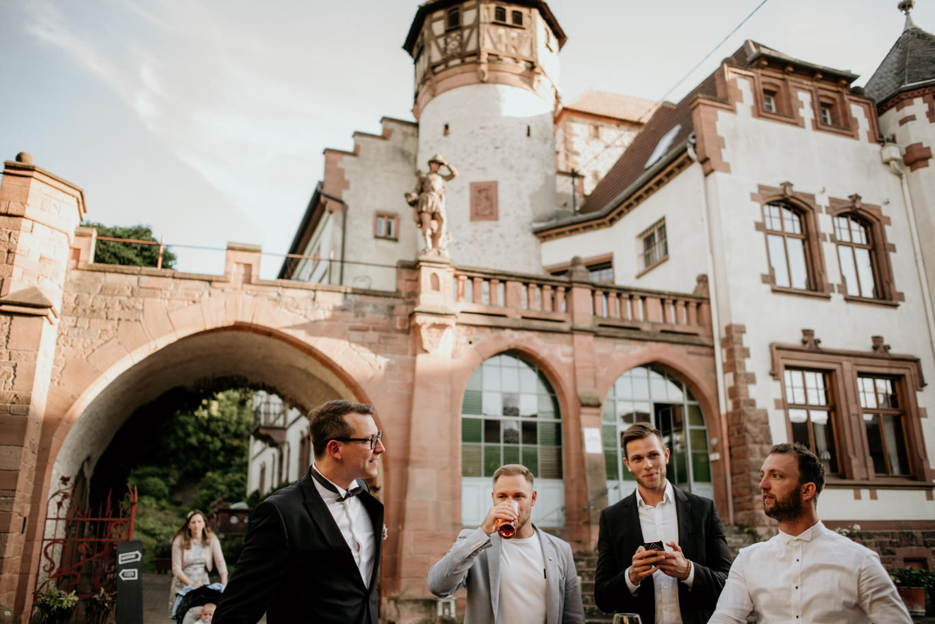 Gäste stehen unter dem Torbogen des Schlossguts Lüll bei Sonnenuntergang