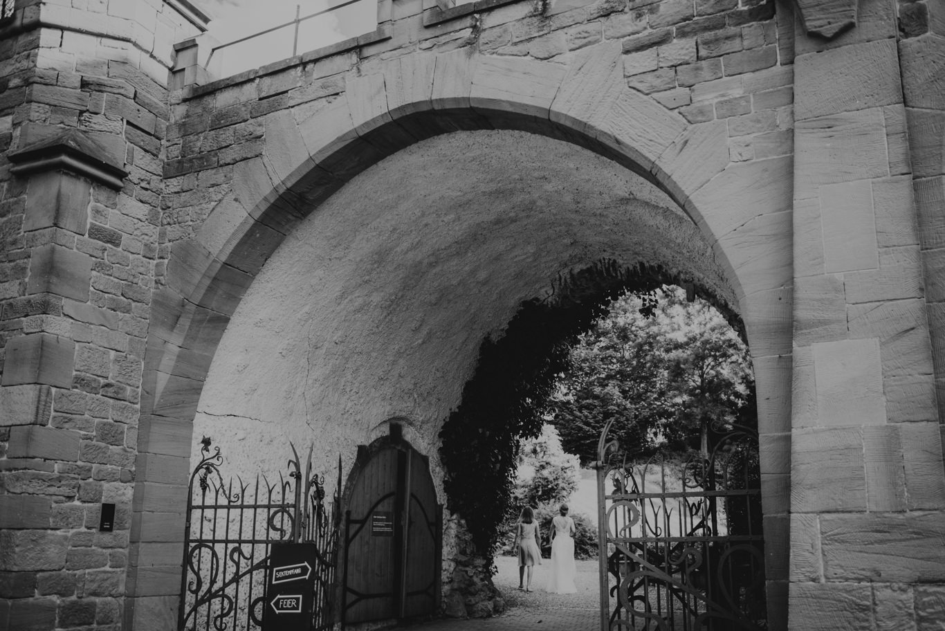 Blick durch einen historischen Torbogen in den Innenhof, Schwarzweißaufnahme