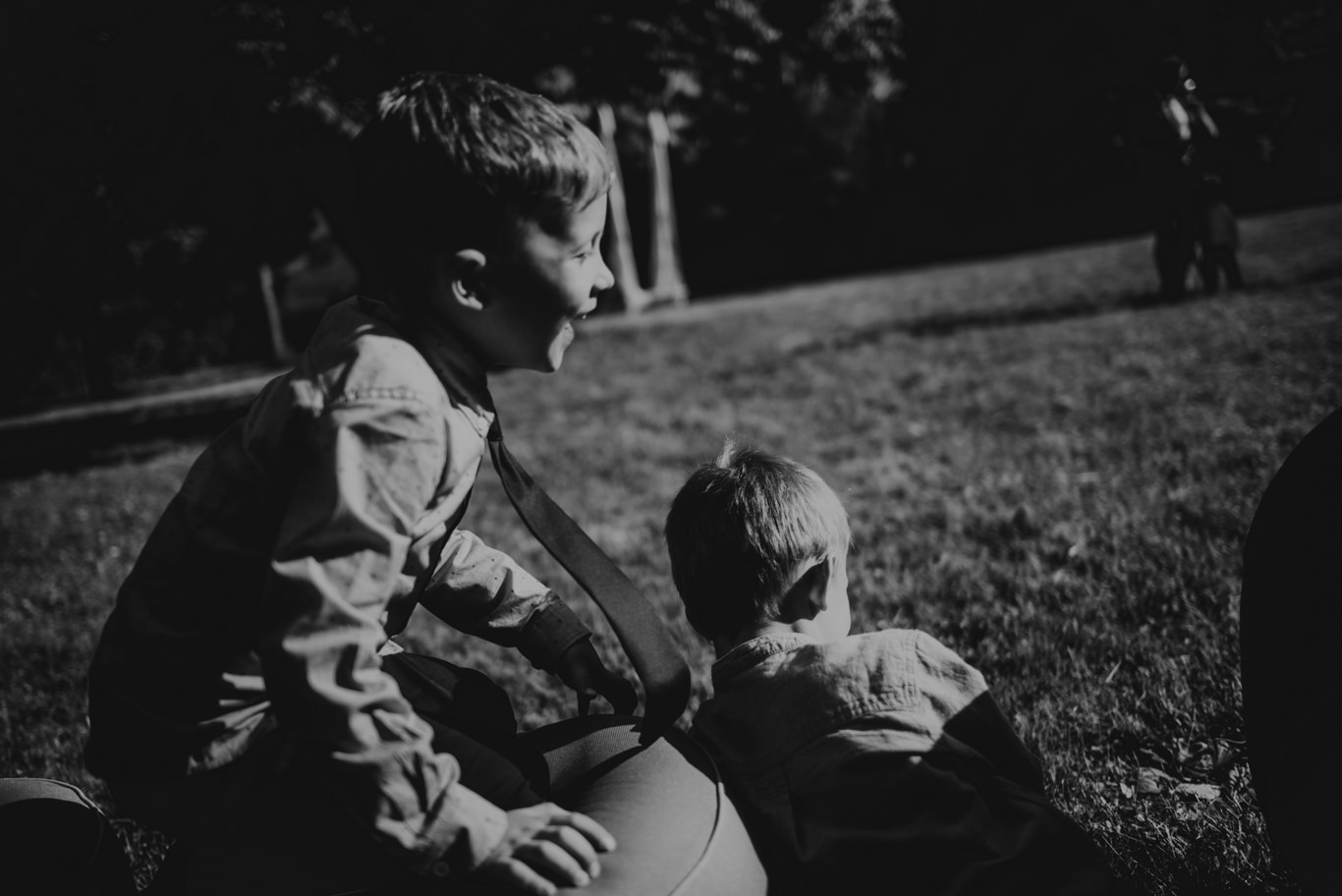 Schwarzweißaufnahme zweier Jungen, die sich im Gras unterhalten