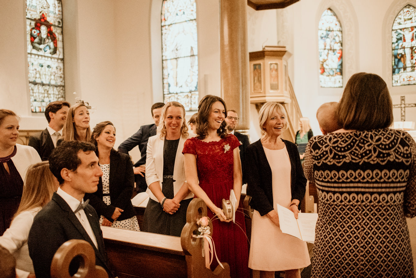 Gäste stehen singend in den Kirchenbänken während der Trauung