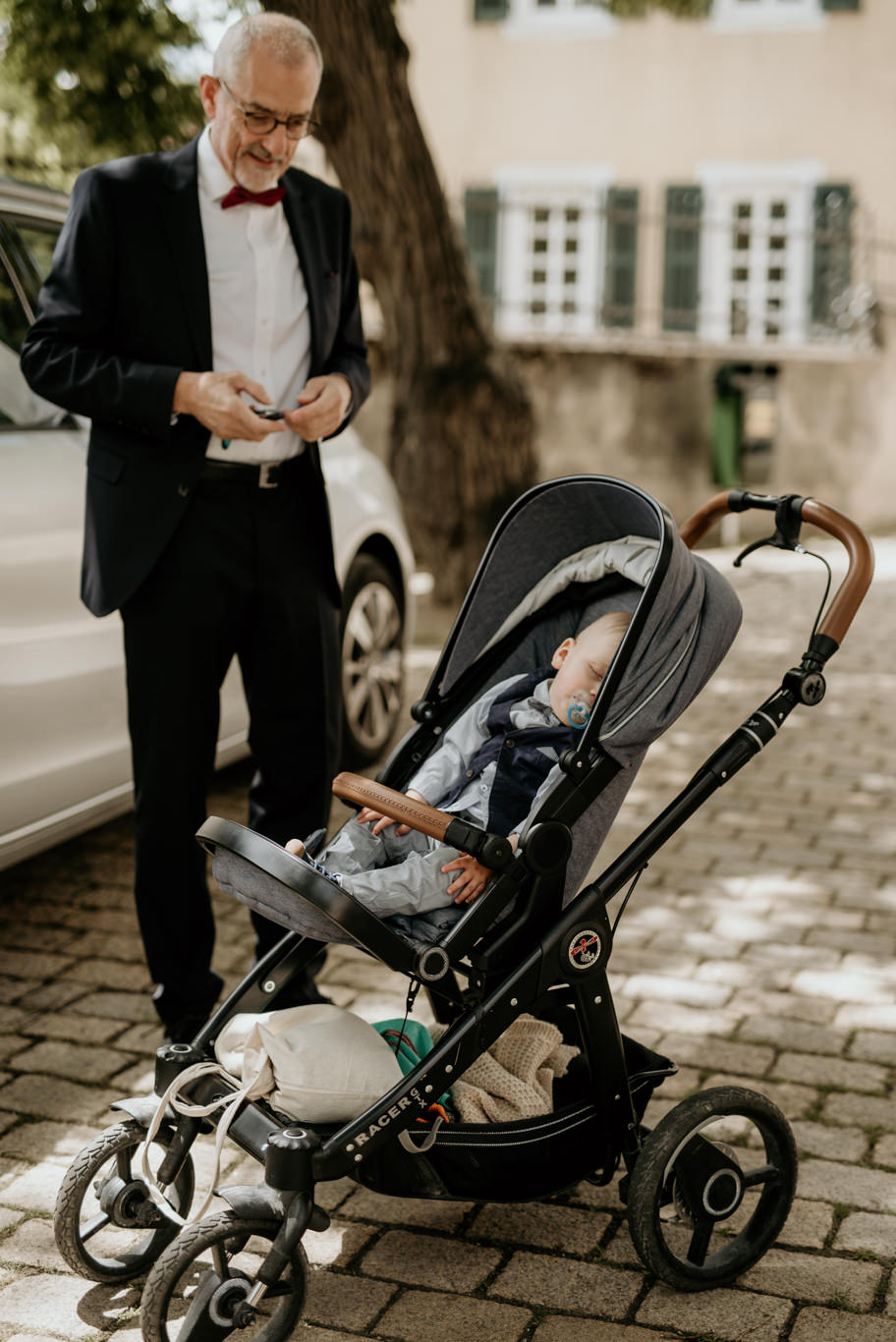 Mann steht neben einem Kinderwagen vor der Kirche