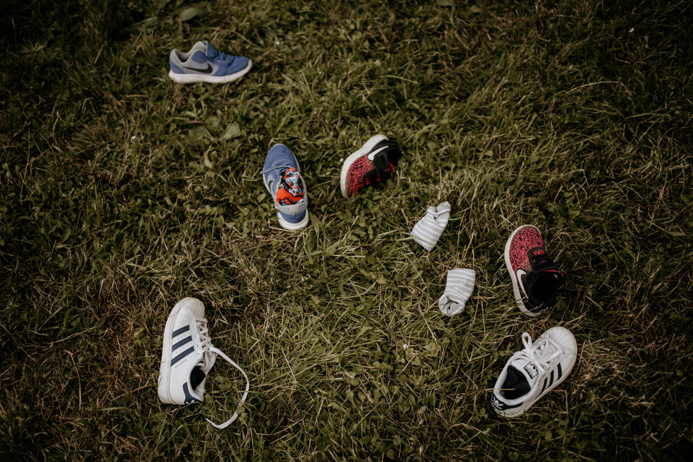 Kinderschuhe liegen paarweise im Gras verteilt