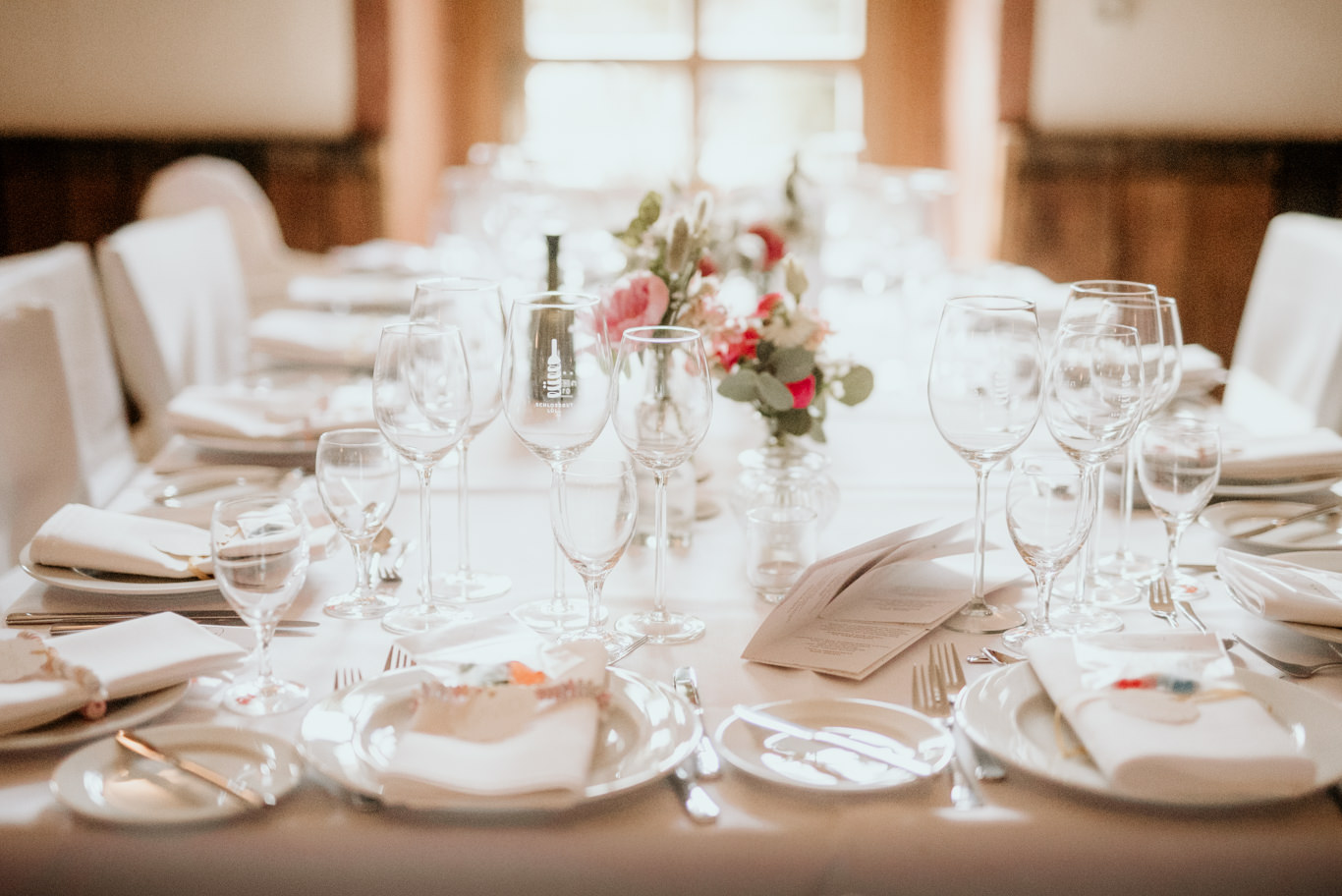 Festlich gedeckter Tisch mit Gläsern und roten Blumen