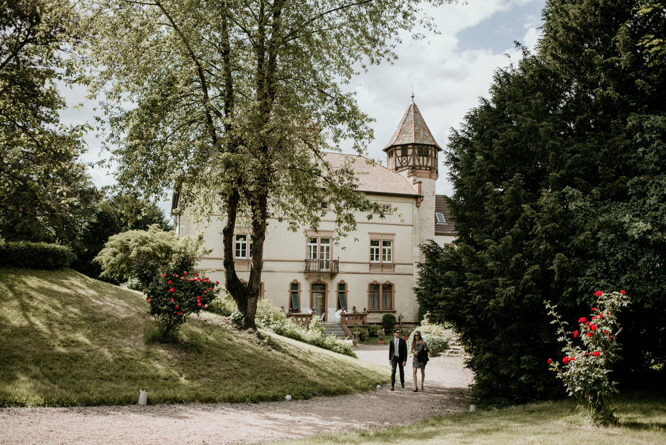 Schlossgebäude mit Türmchen hinter grünen Bäumen im Park