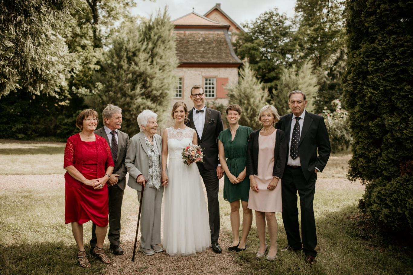 Familie posiert gemeinsam vor historischem Gebäude im Garten