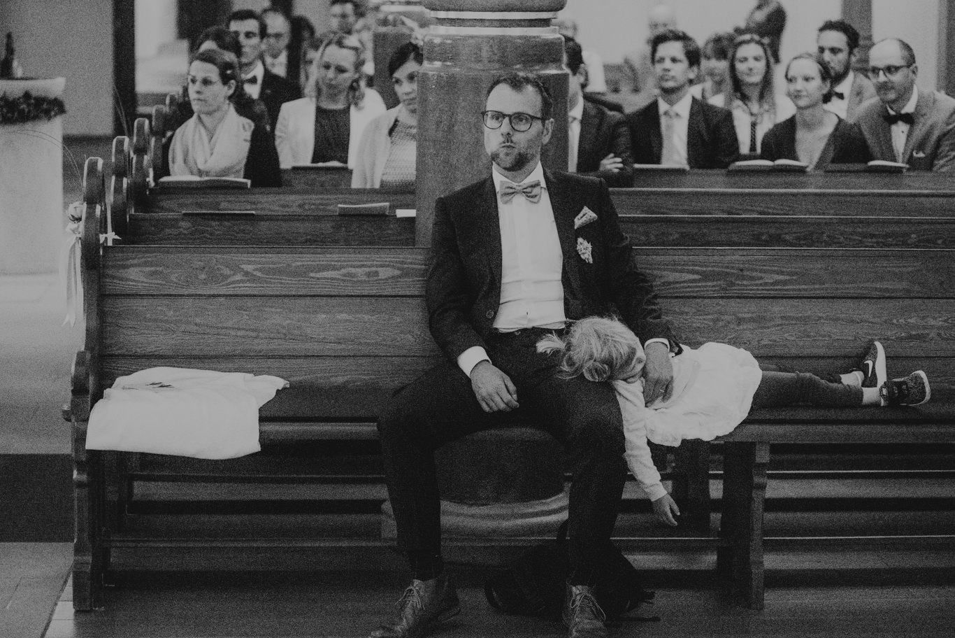 Schwarzweißaufnahme eines Mannes, der neben einem schlafenden Baby sitzt
