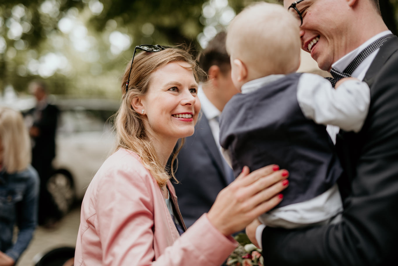 Gästin lacht mit einem Mann, der ein Baby trägt