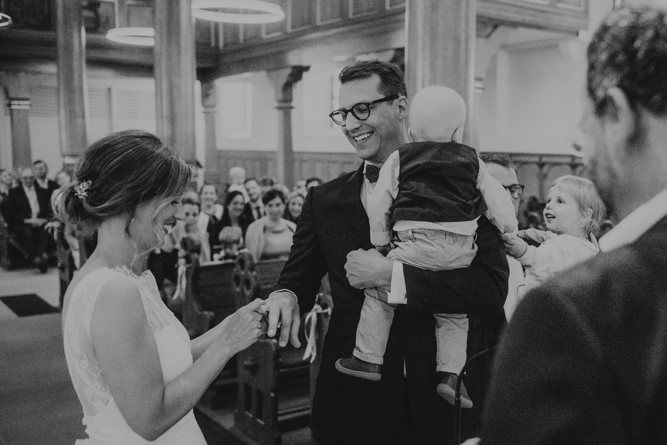 Schwarzweißaufnahme eines Vaters, der sein Baby in der Kirche trägt