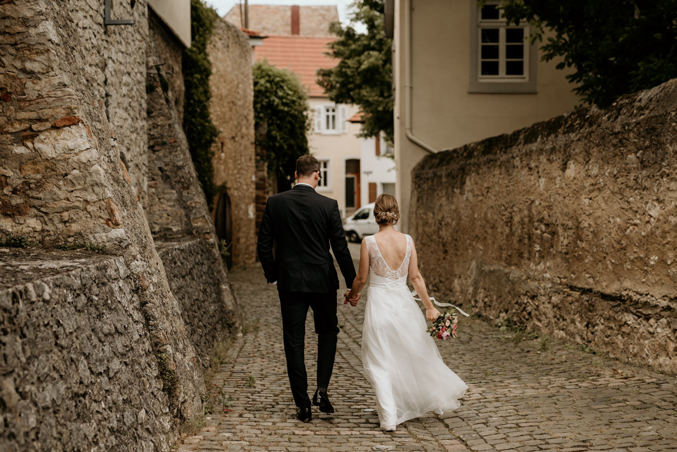 Brautpaar geht Hand in Hand durch die schmale Gasse