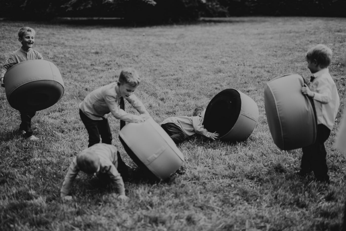 Schwarzweißaufnahme spielender Kinder mit großen Sitzsäcken auf der Wiese
