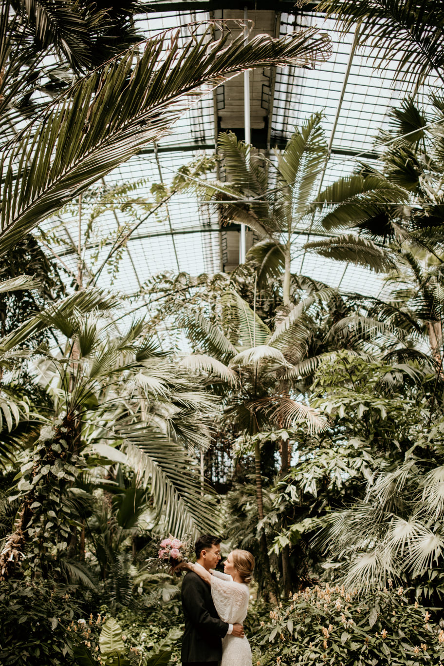 Brautpaar küsst sich unter tropischen Pflanzen im Palmengarten Frankfurt