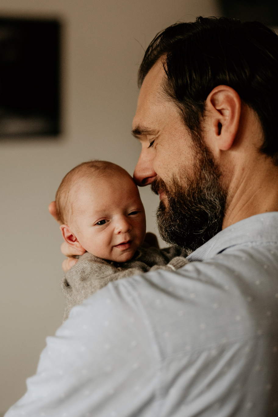 Vater trägt sein Baby auf dem Arm und lächelt es an