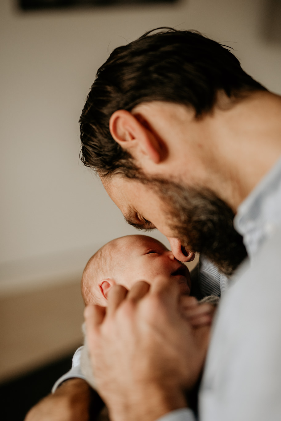 Vater berührt lächelnd mit der Stirn sein Baby