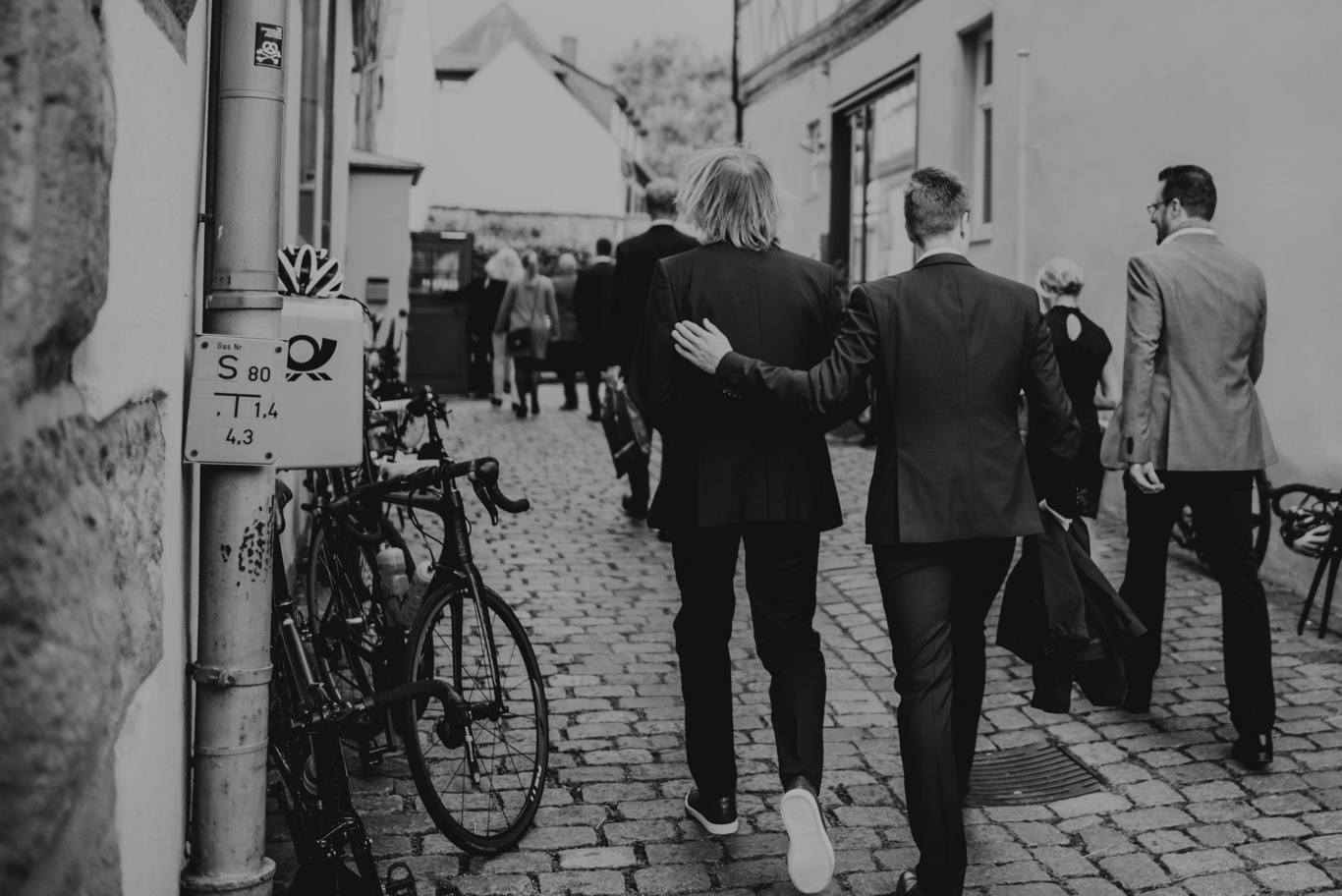 Hochzeitsgesellschaft geht durch schmale Altstadtgasse, Schwarzweißaufnahme