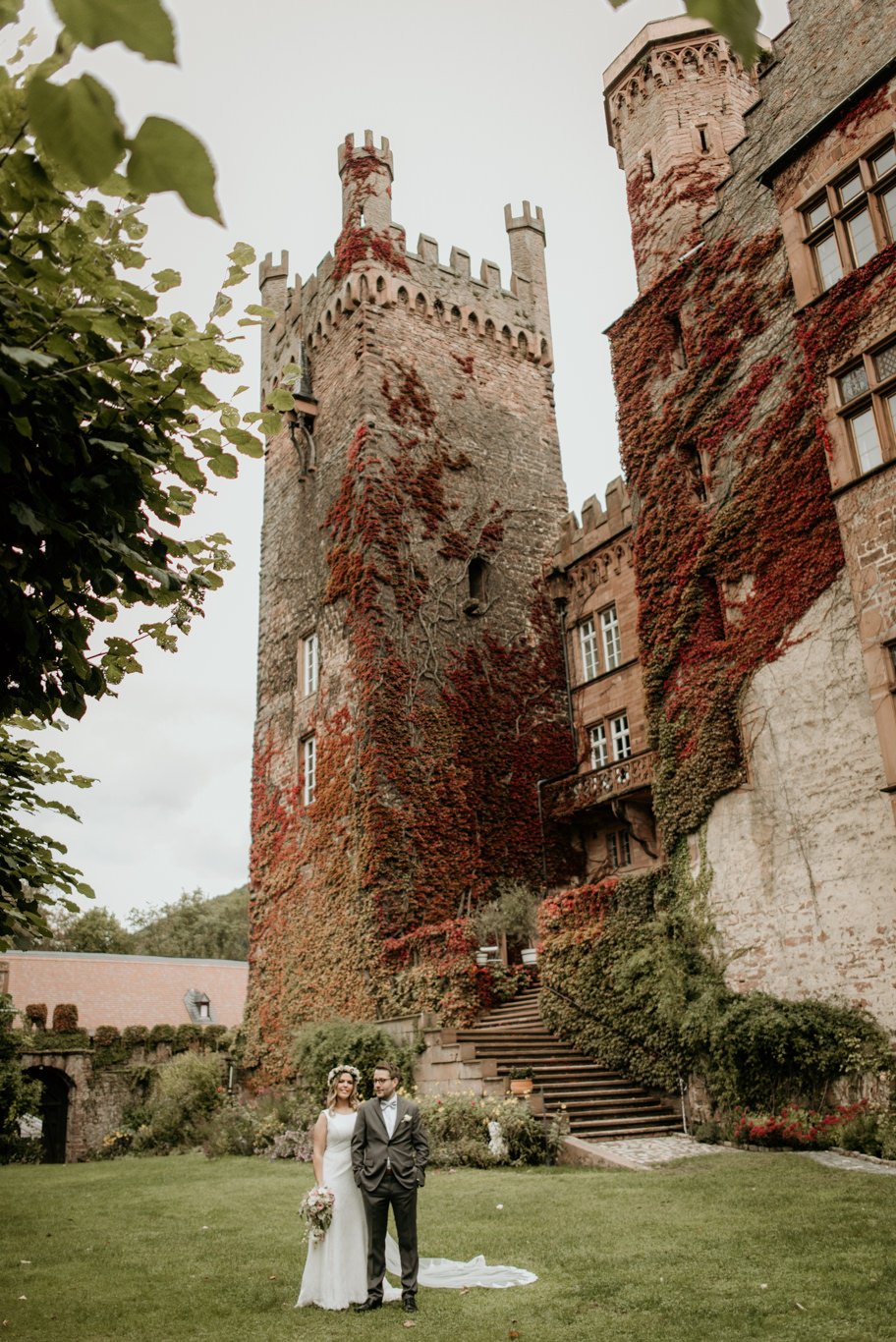 Brautpaar steht klein vor dem mächtigen Turm der Mittelburg