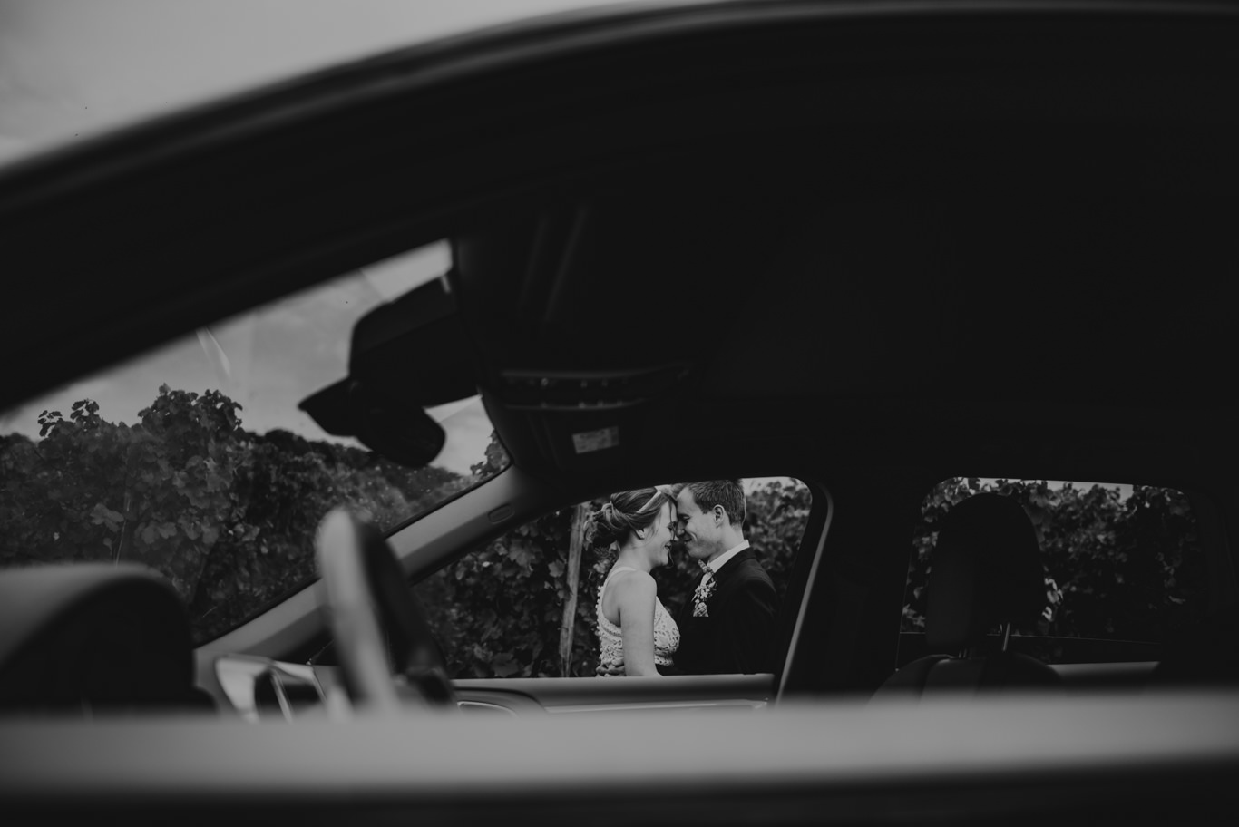 Braut sitzt im Oldtimer, Blick durchs Autofenster, Schwarzweißaufnahme