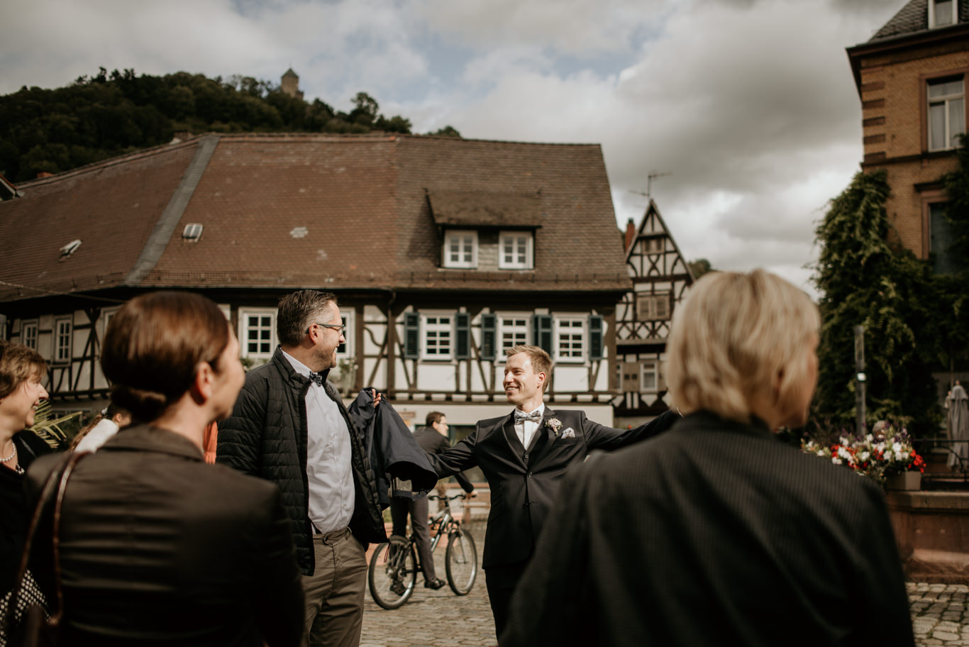 Bräutigam schüttelt die Hand des Brautvaters vor Fachwerkhäusern am Marktplatz