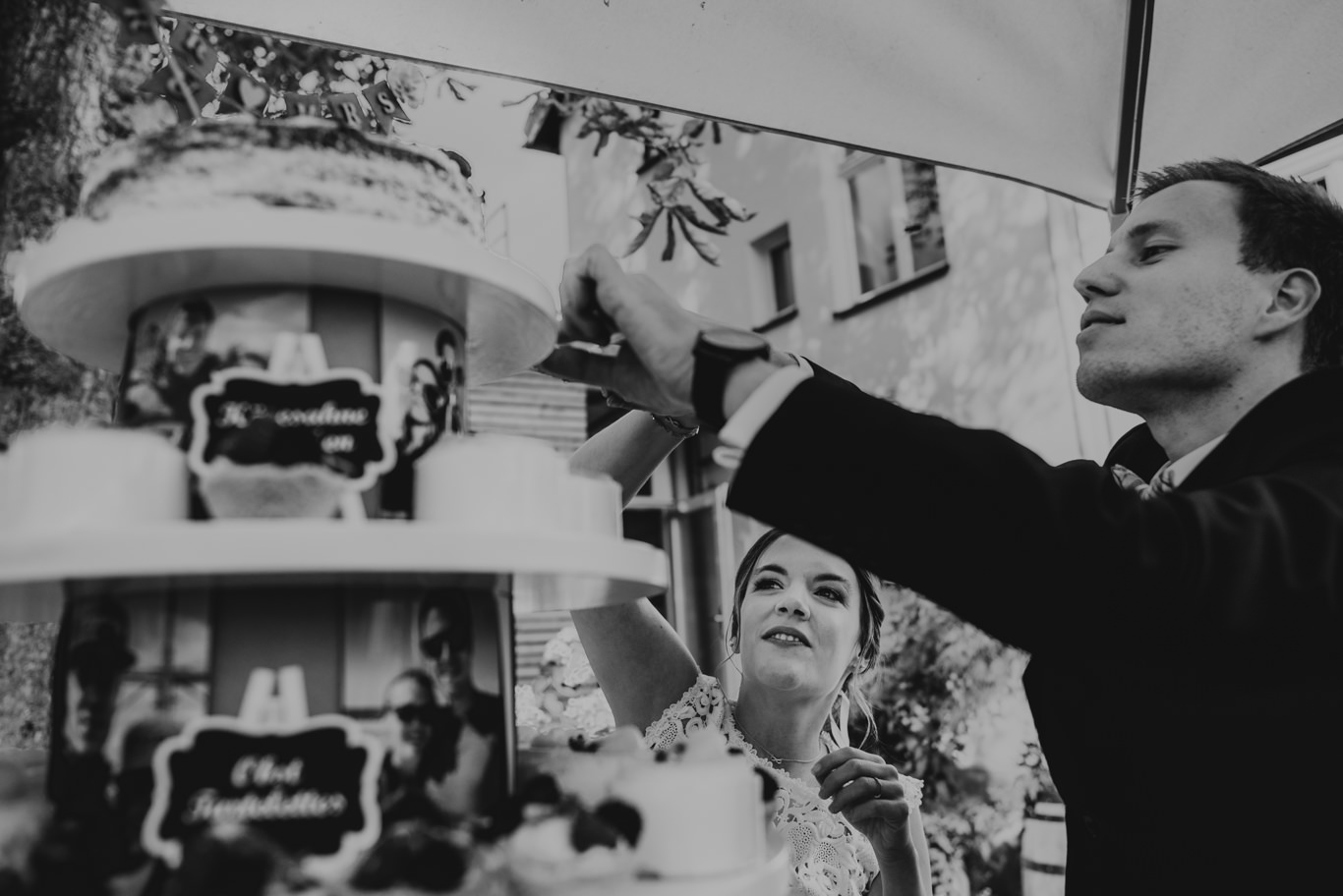 Bräutigam reicht Braut Stück Hochzeitstorte unter Sonnenschirm, Schwarzweißaufnahme