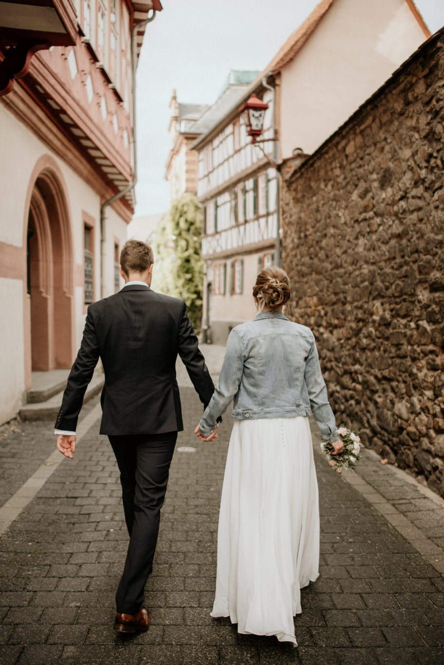 Brautpaar geht Hand in Hand durch eine Altstadtgasse