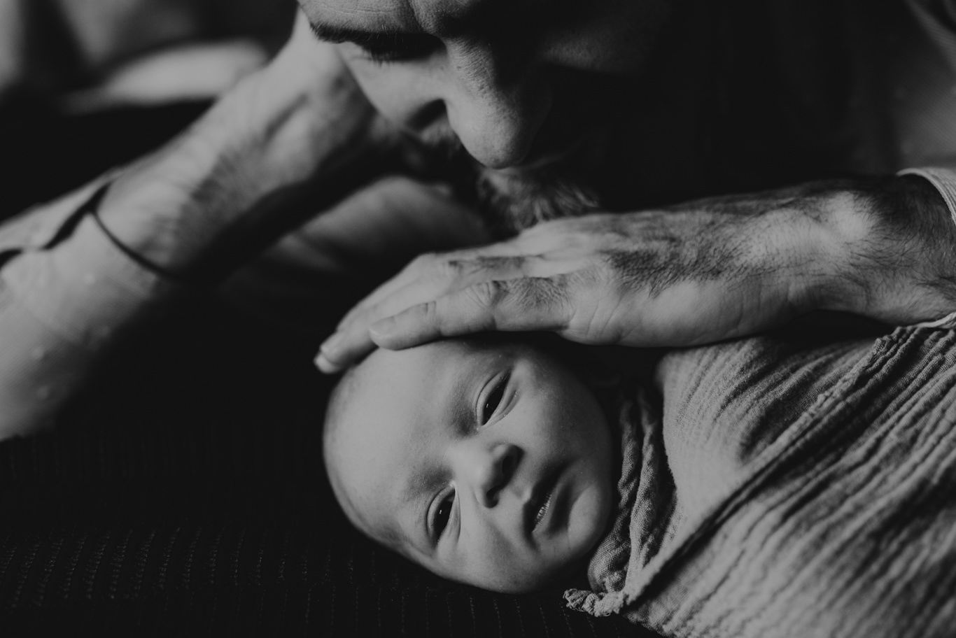 Vater streichelt sanft den Kopf seines schlafenden Babys, Schwarzweißaufnahme
