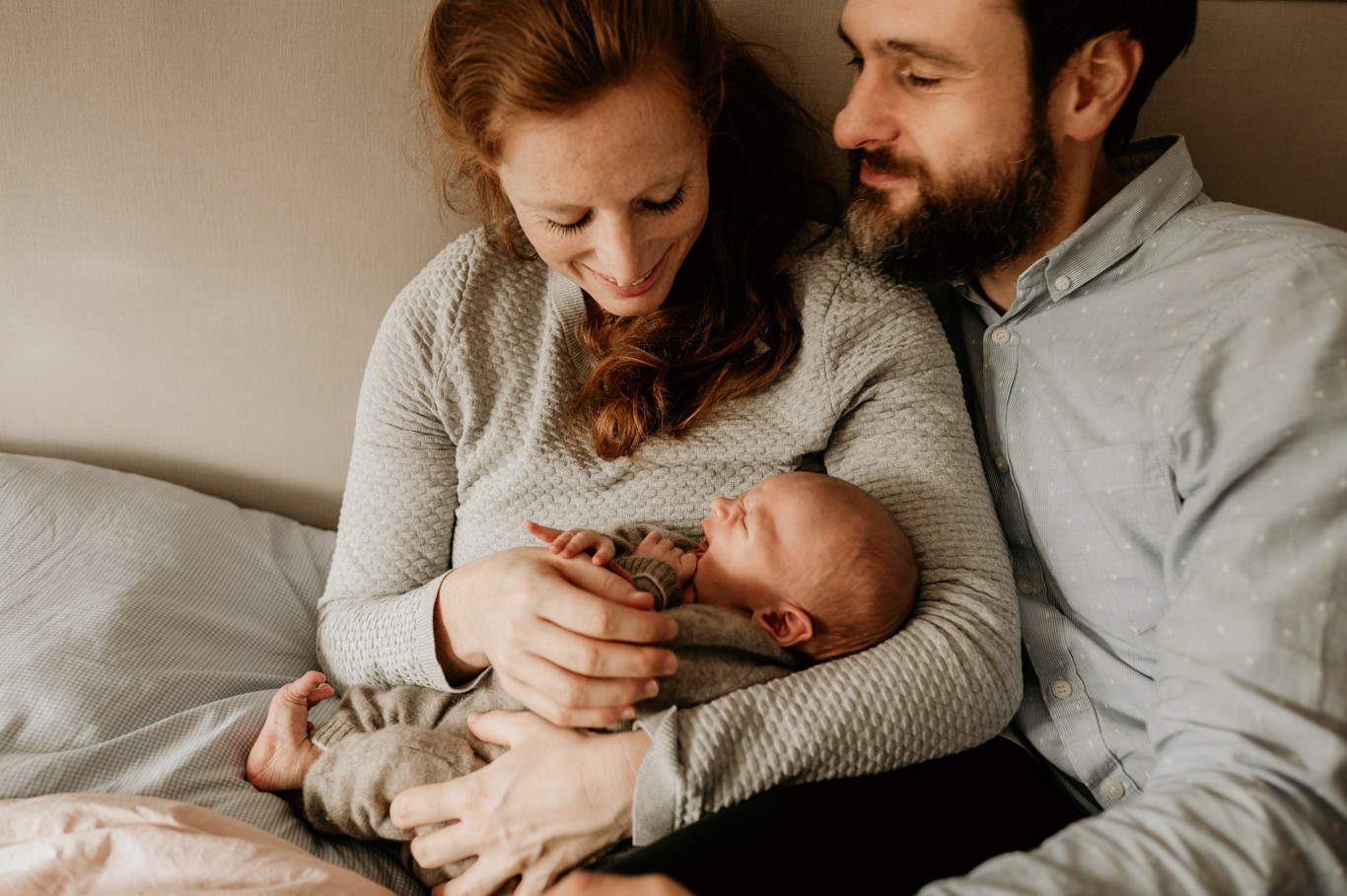 Mutter und Vater betrachten lächelnd ihr neugeborenes Baby
