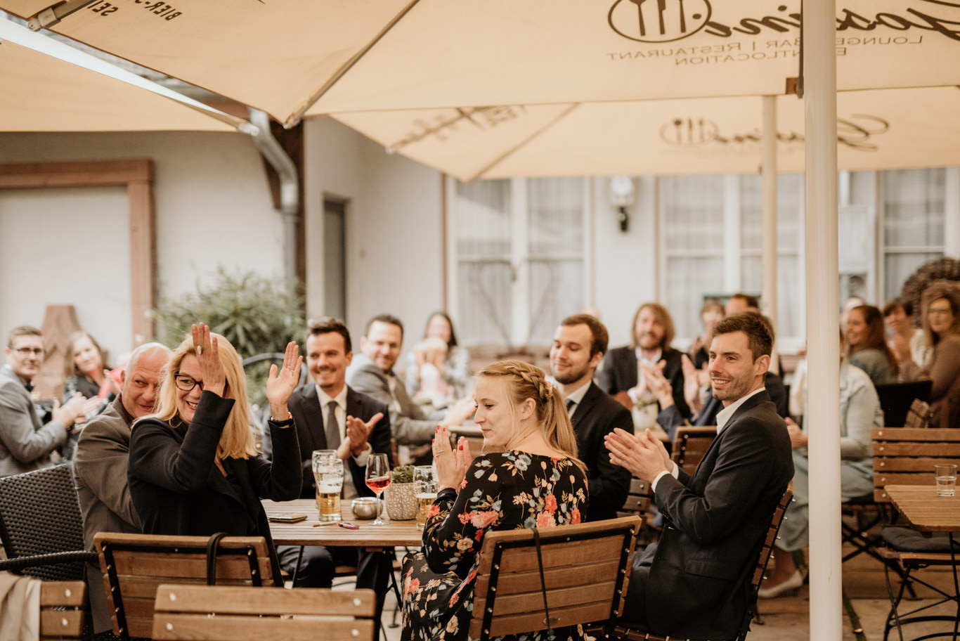 Hochzeitsgäste applaudieren an gedeckten Tischen im Freien