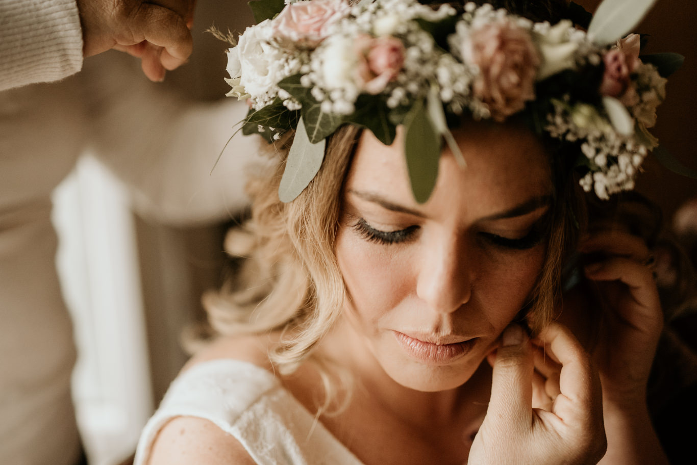 Jemand steckt der Braut den Blumenkranz ins Haar