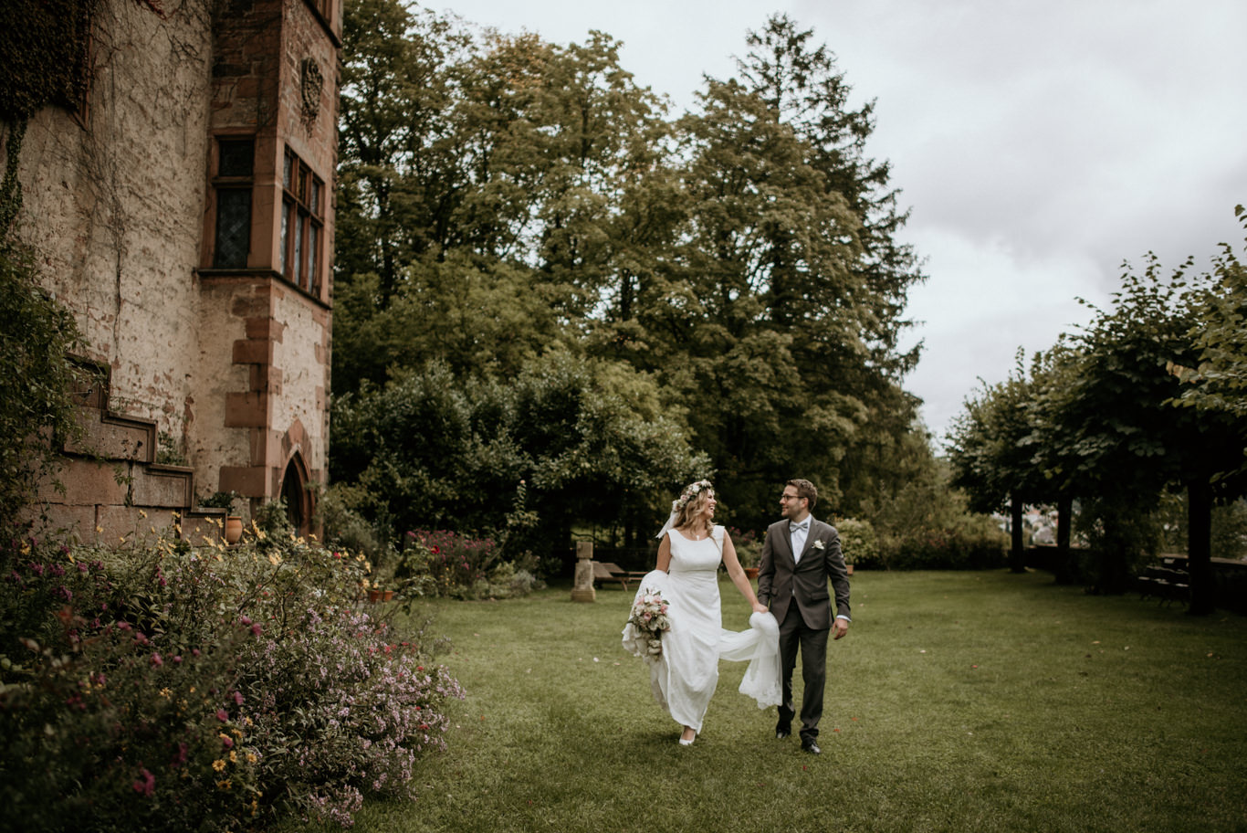 Brautpaar läuft Hand in Hand über die Wiese der Mittelburg