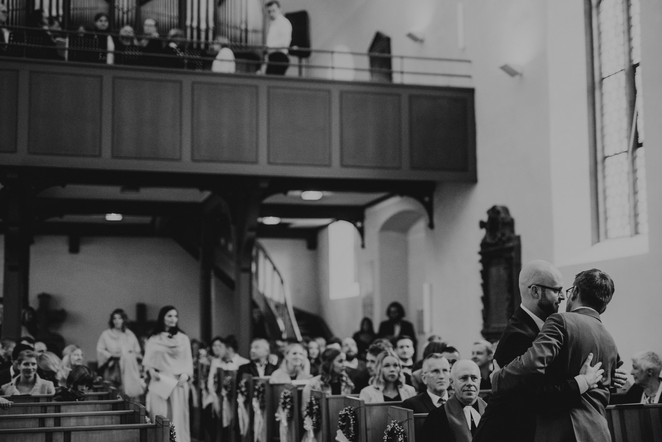 Schwarzweißaufnahme der Trauzeugen in der Kirche vor der Zeremonie