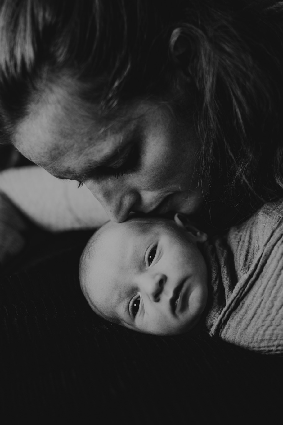 Mutter küsst ihr Baby zärtlich auf die Stirn, Schwarzweißaufnahme