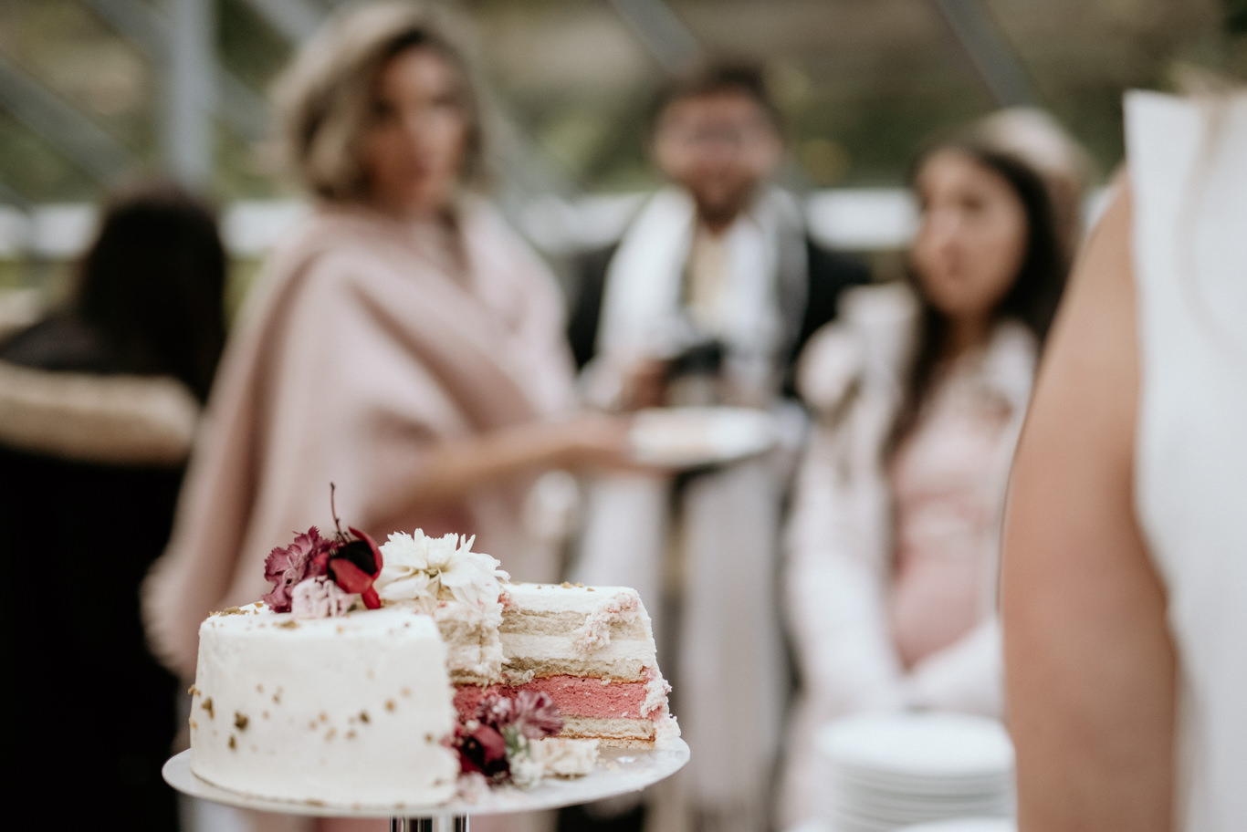 Gäste stehen an einem Tisch mit mehrstöckiger Hochzeitstorte