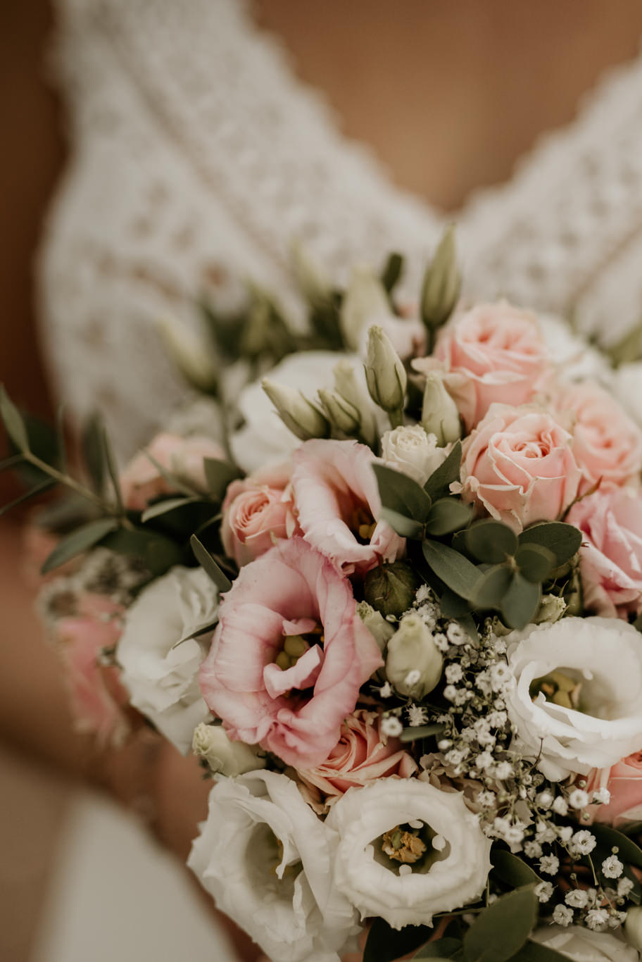 Brautstrauß aus rosa und weißen Blüten in Brauthänden