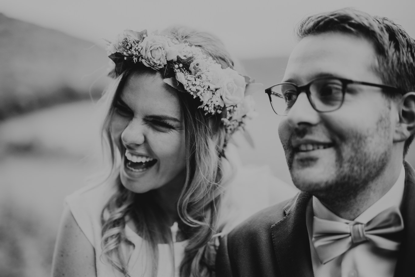 Braut mit Blumenkranz lacht ihren Bräutigam an, Schwarzweißaufnahme