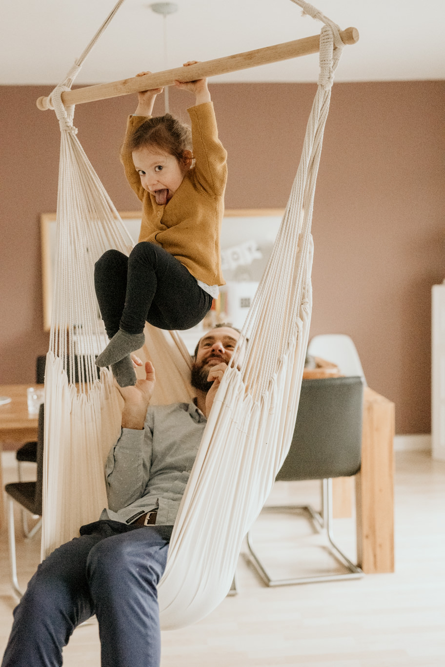 Kind hängt lachend in einer Hängematte, Vater sitzt darunter