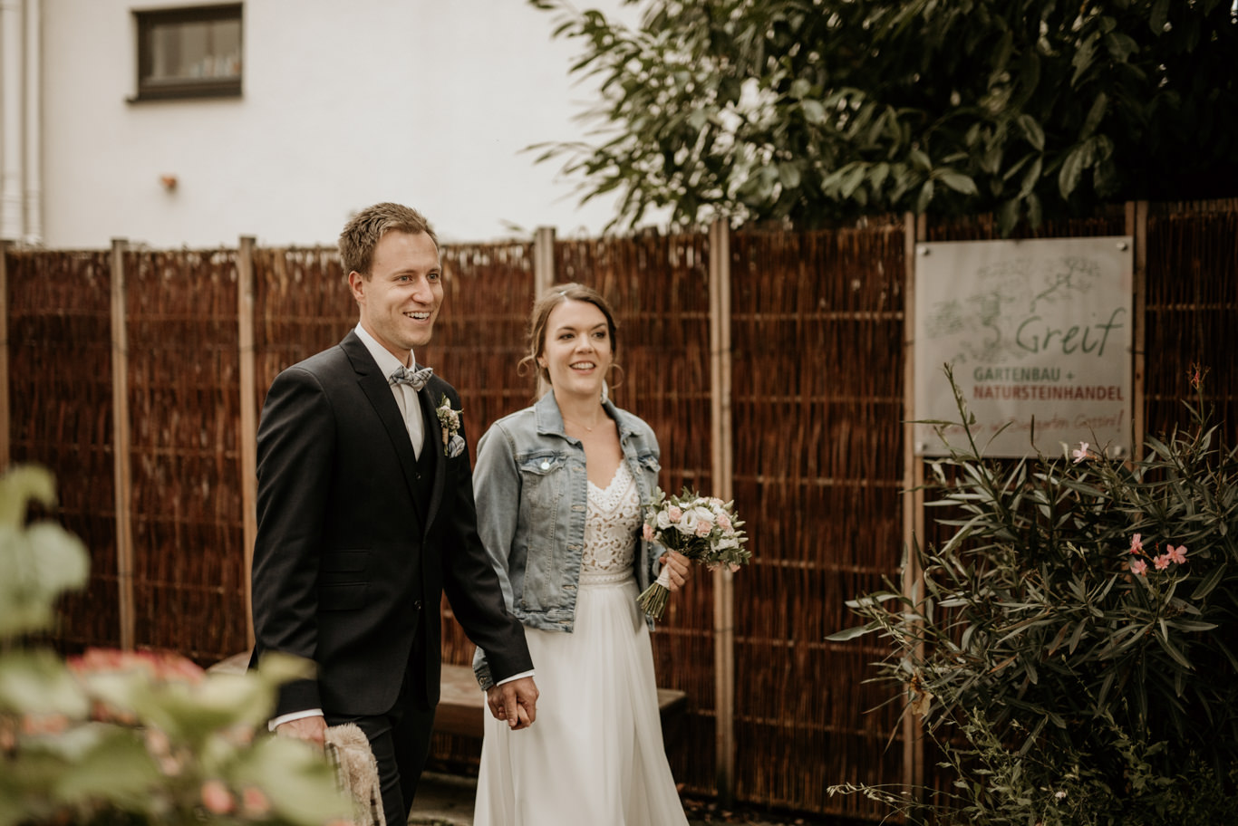 Brautpaar geht Arm in Arm durch einen Garten