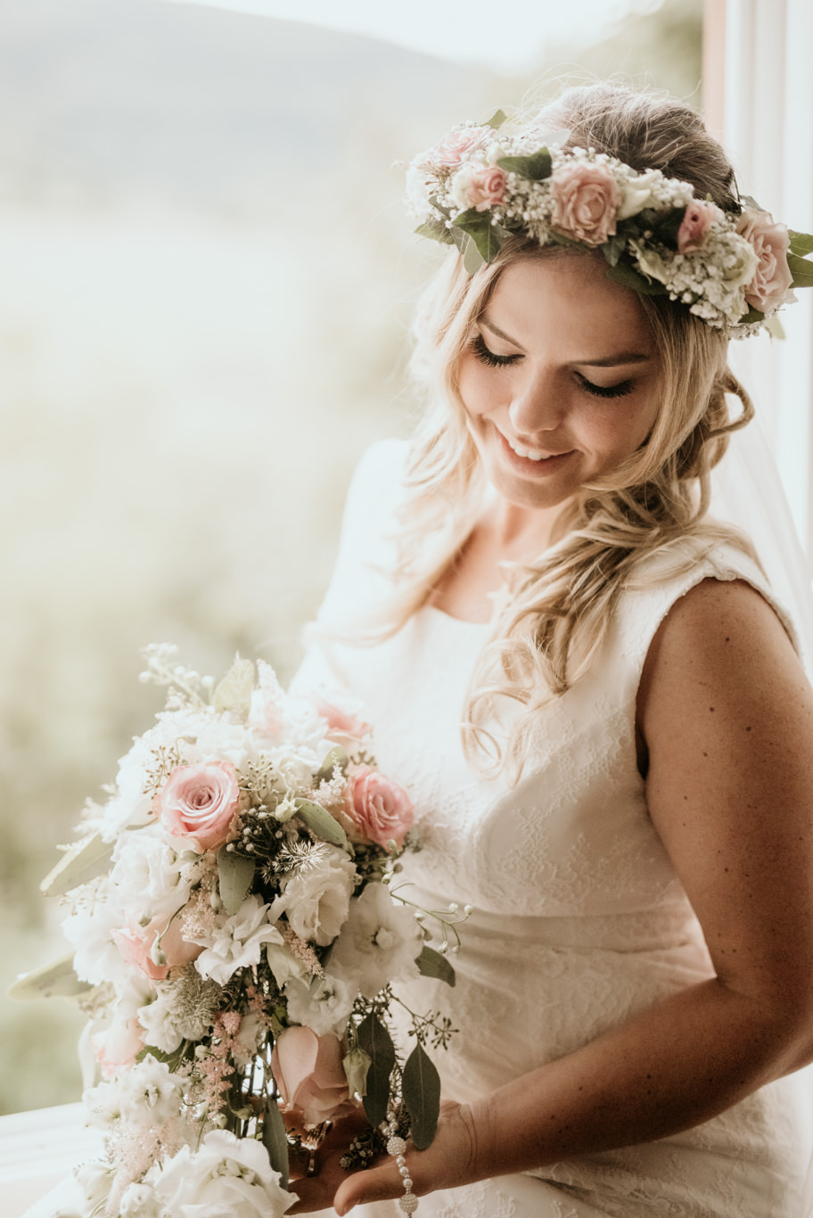 Braut mit Blumenkranz hält lächelnd ihren Brautstrauß