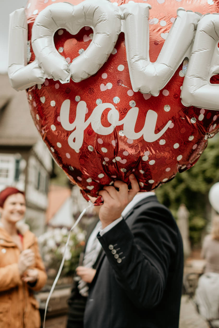 Gast hält einen herzförmigen Luftballon mit der Aufschrift Love You