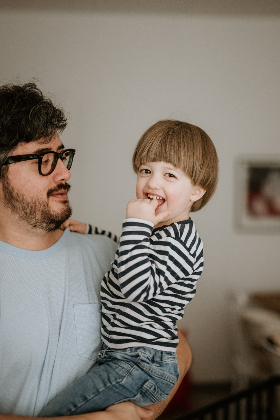 Vater hält lächelndes Kleinkind auf dem Arm in der Wohnung