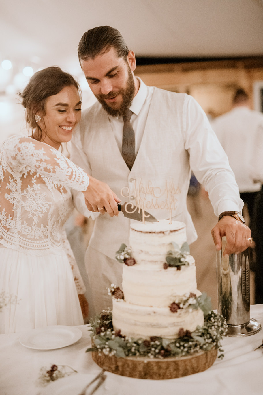 Brautpaar schneidet lachend die Hochzeitstorte gemeinsam an
