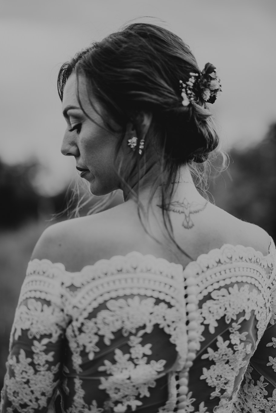 Schwarzweißaufnahme, Braut im Spitzenkleid von hinten mit Blumen im Haar