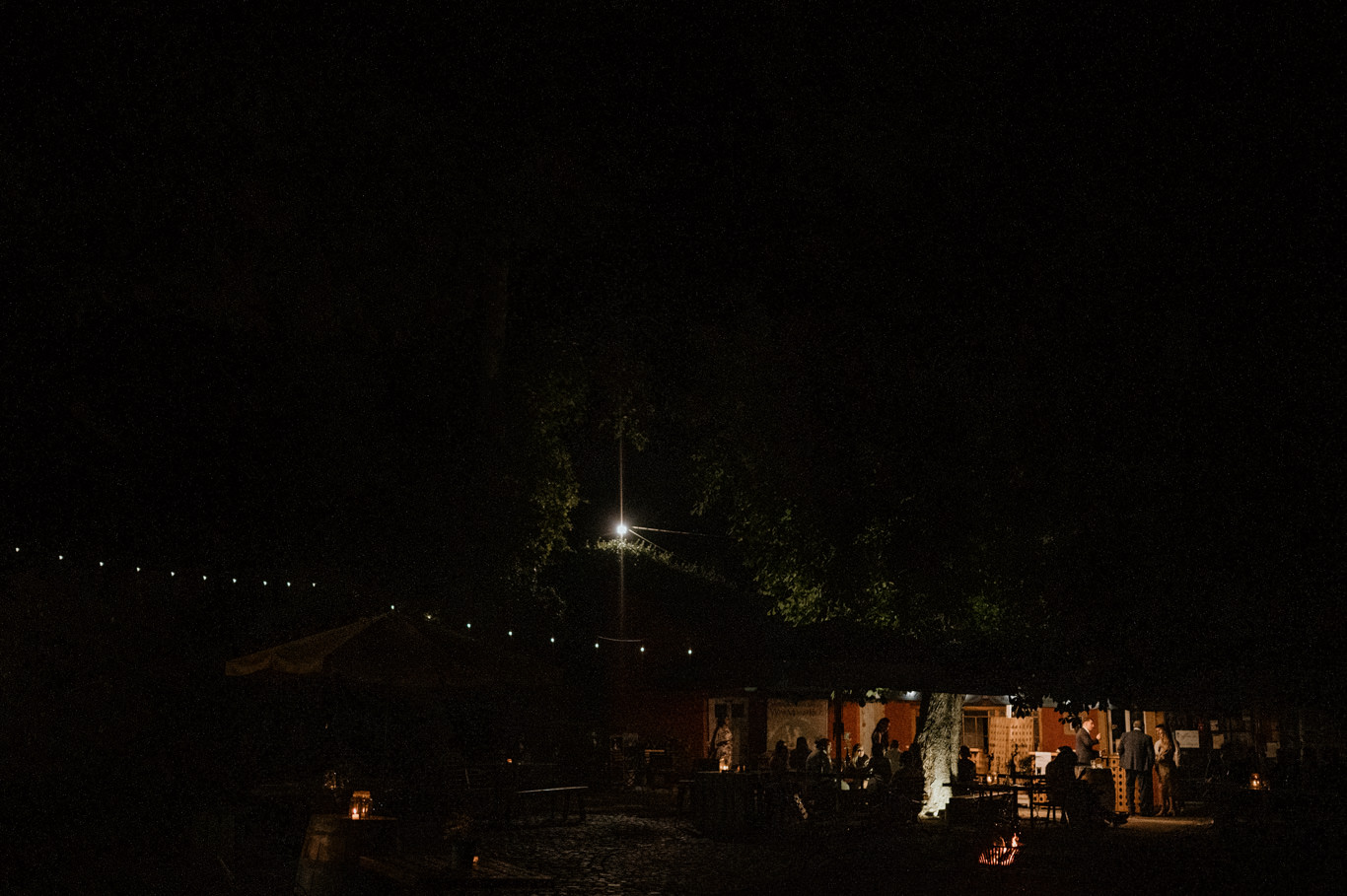 Beleuchtetes Festzelt liegt nachts im Garten unter Lichterketten