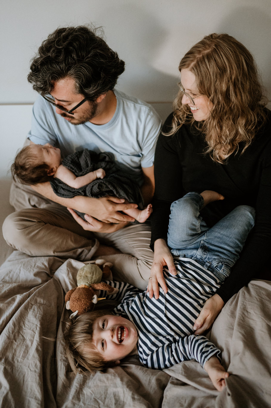 Eltern halten Baby und Kind im Arm auf dem Bett