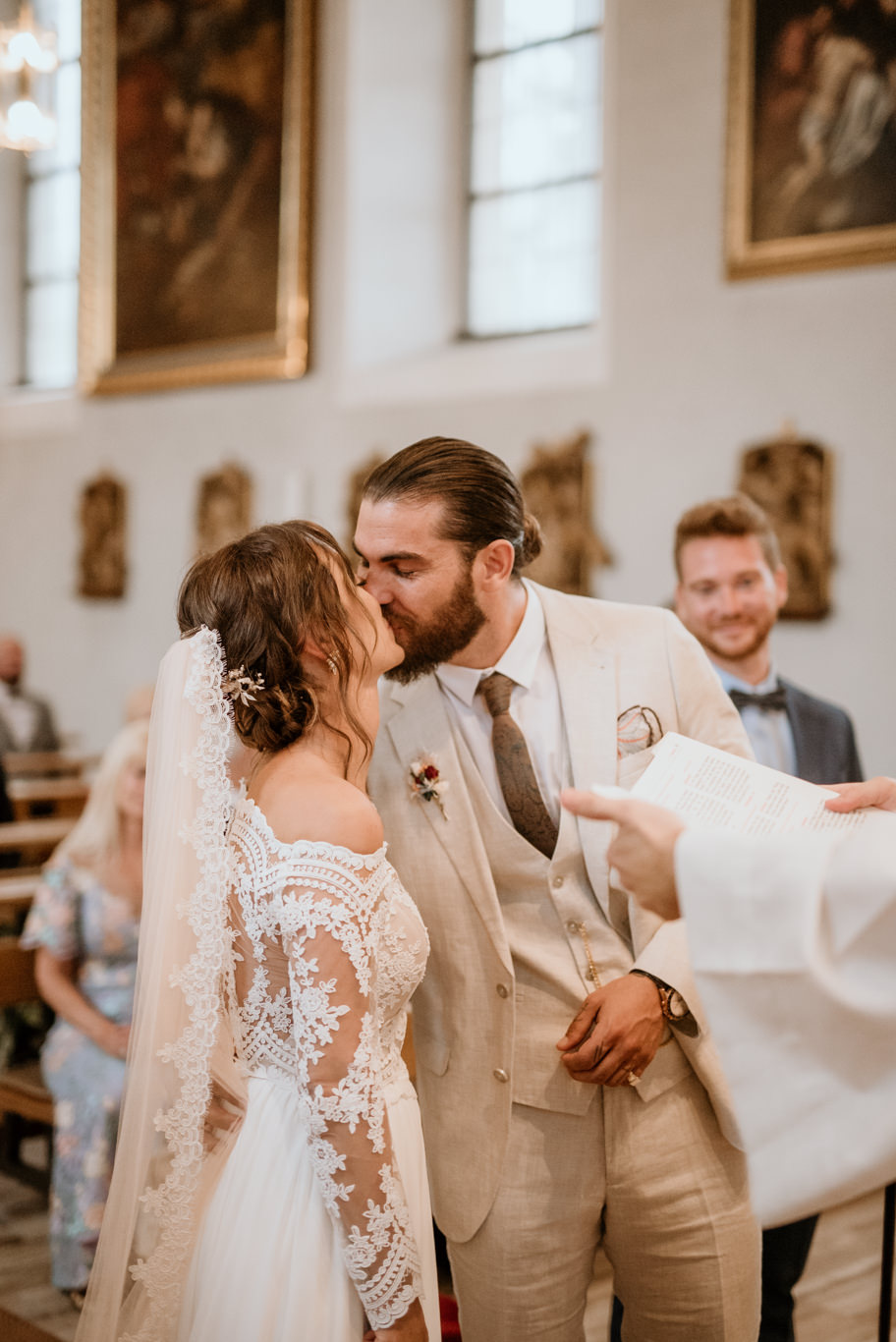 Brautpaar küsst sich vor dem Priester in der Kirche