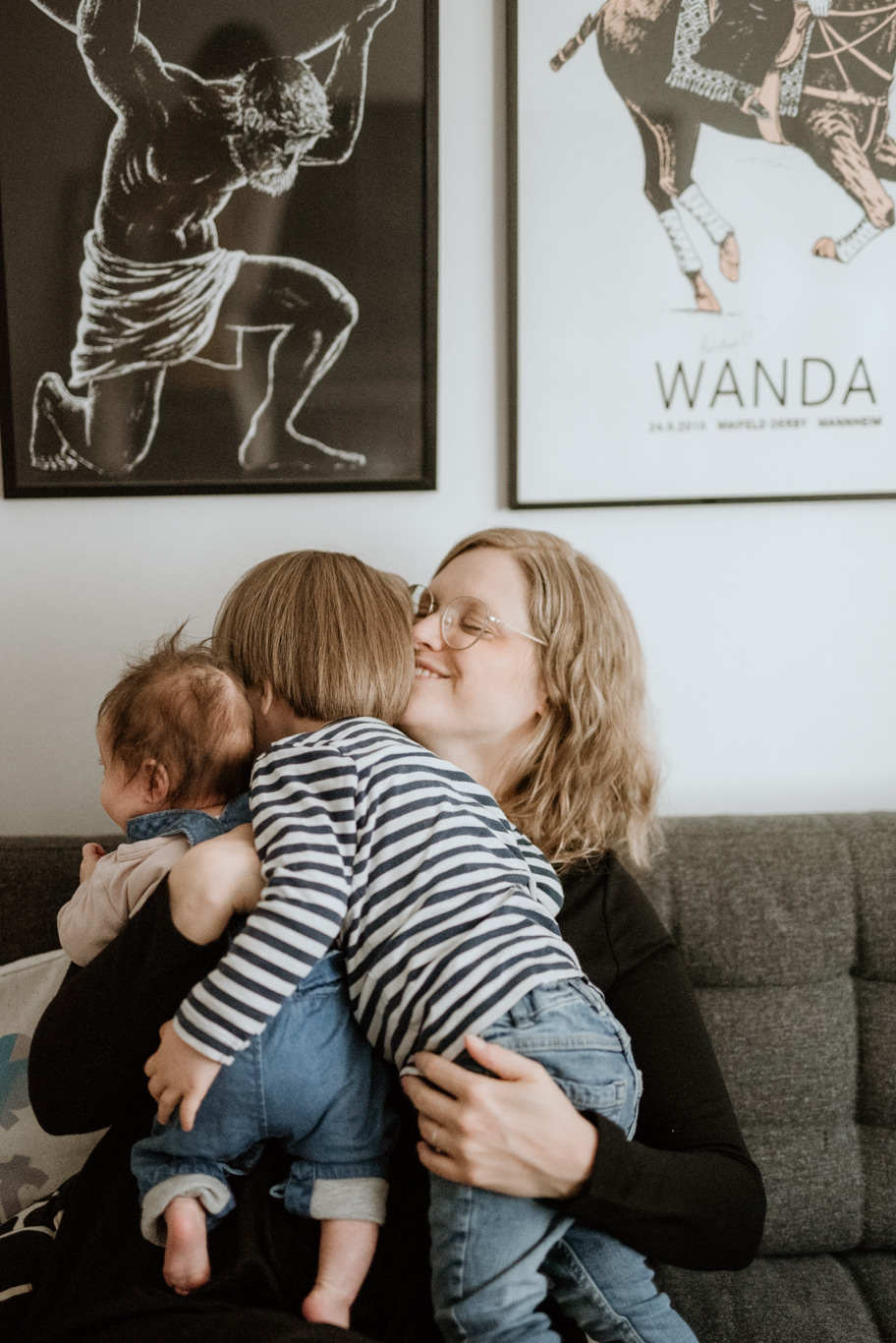 Mutter drückt ihr Baby liebevoll an sich, Sohn lehnt sich an