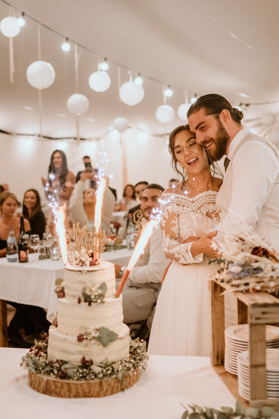 Brautpaar zündet gemeinsam Wunderkerzen an der Hochzeitstorte an