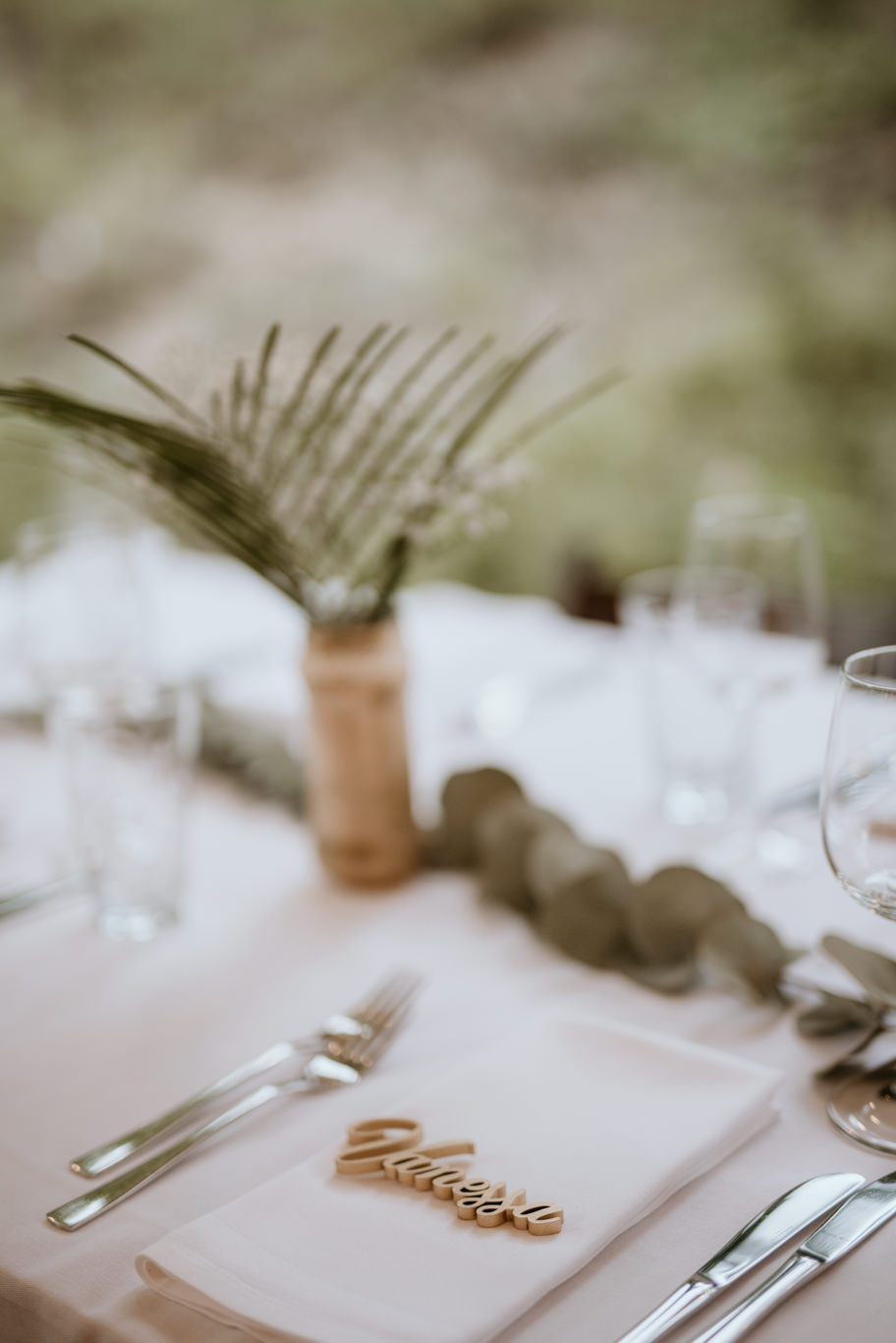 Namenskärtchen und Palmzweig auf gedecktem Tisch